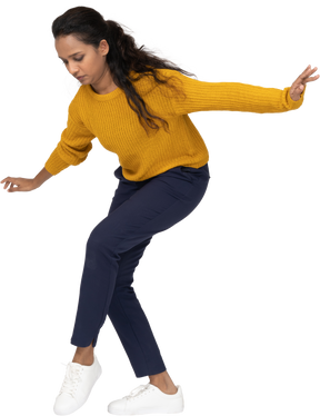 Side view of a girl in casual clothes posing on one leg with outstretched arms