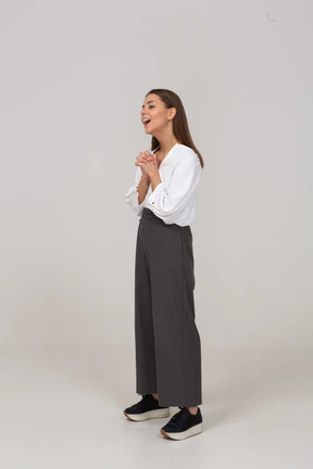 Three-quarter view of an excited young lady in office clothing holding hands together