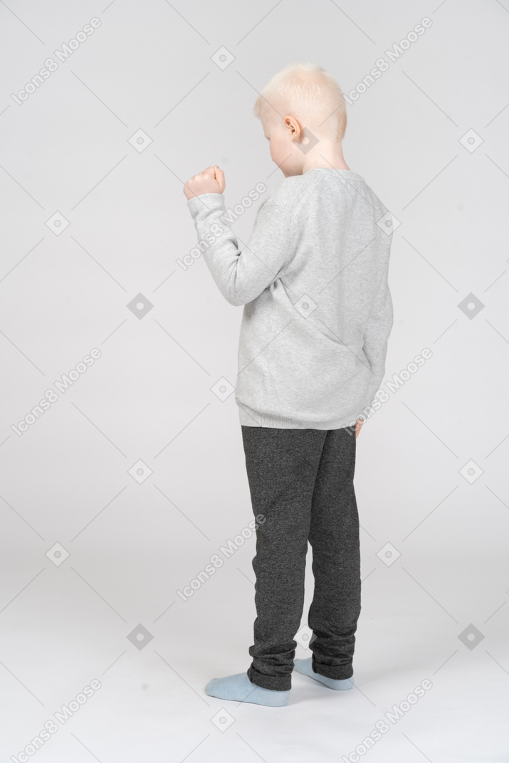 Petit garçon debout avec son poing levé