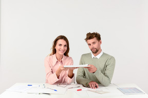 Female and male architects sitting at the table and holding tablet
