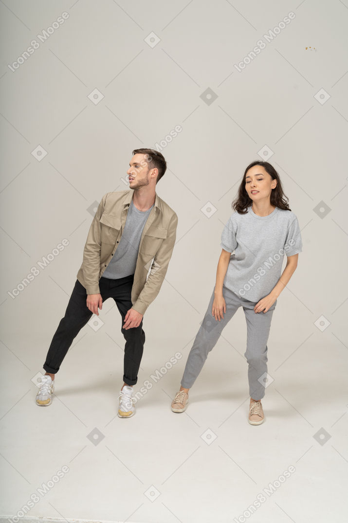 Vista de jovem e mulher apoiando-se em uma perna e olhando de lado