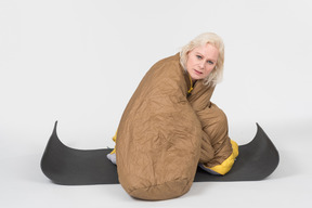 Mature woman sitting on yoga mat wrapped in blanket