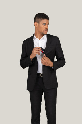 Vorderansicht eines jungen mannes im schwarzen anzug mit bankkarte