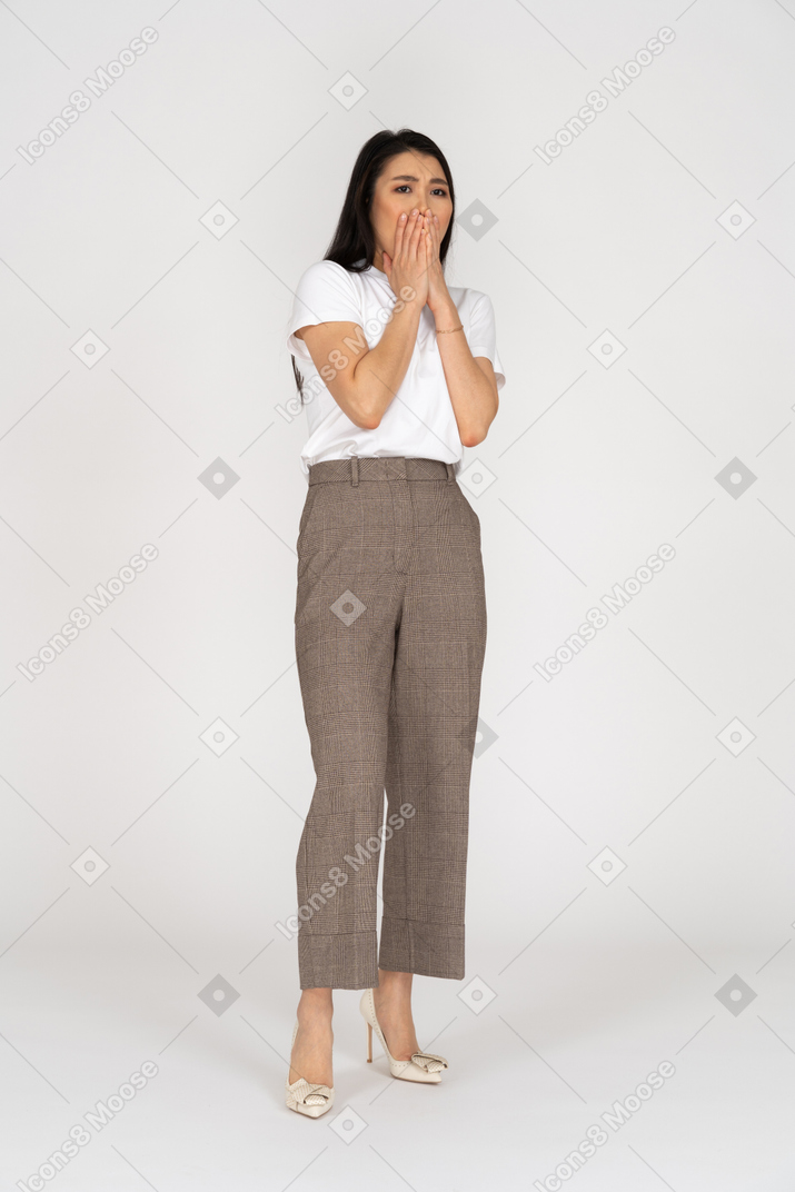 Front view of a scared young lady in breeches and t-shirt touching her mouth