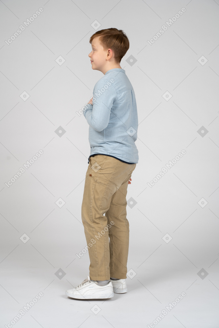 Side view of a cute boy posing with hand on chest