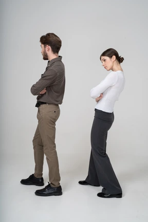 Three-quarter back view of a young couple in office clothing crossing arms