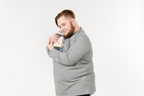 Bid bearded man hugging jar with marshmallows with his eyes closed