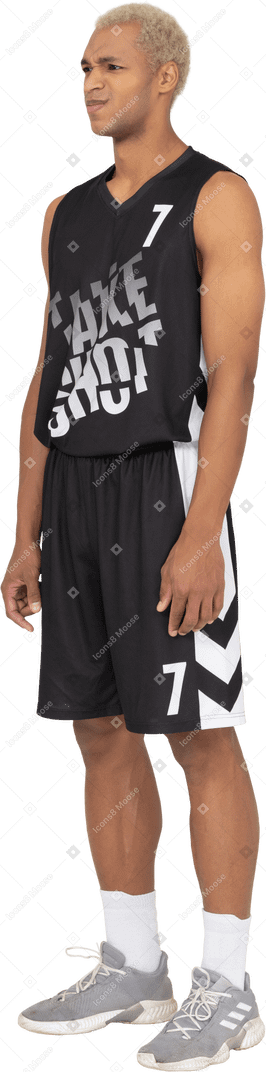 Vista de tres cuartos de un joven jugador de baloncesto masculino disgustado parado