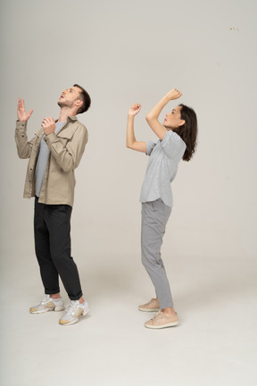 Man and woman looking up and raising their hands