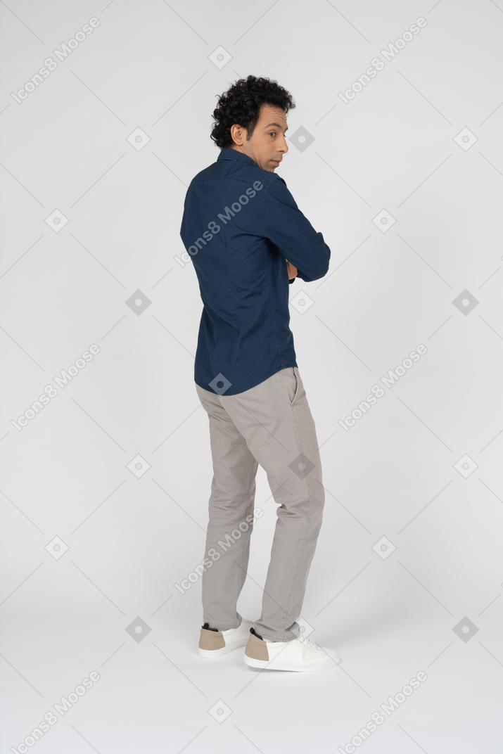 Seitenansicht eines mannes in freizeitkleidung, der mit verschränkten armen posiert
