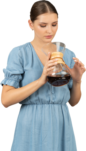 一位身着蓝色连衣裙的年轻女子拿着一壶酒的前视图