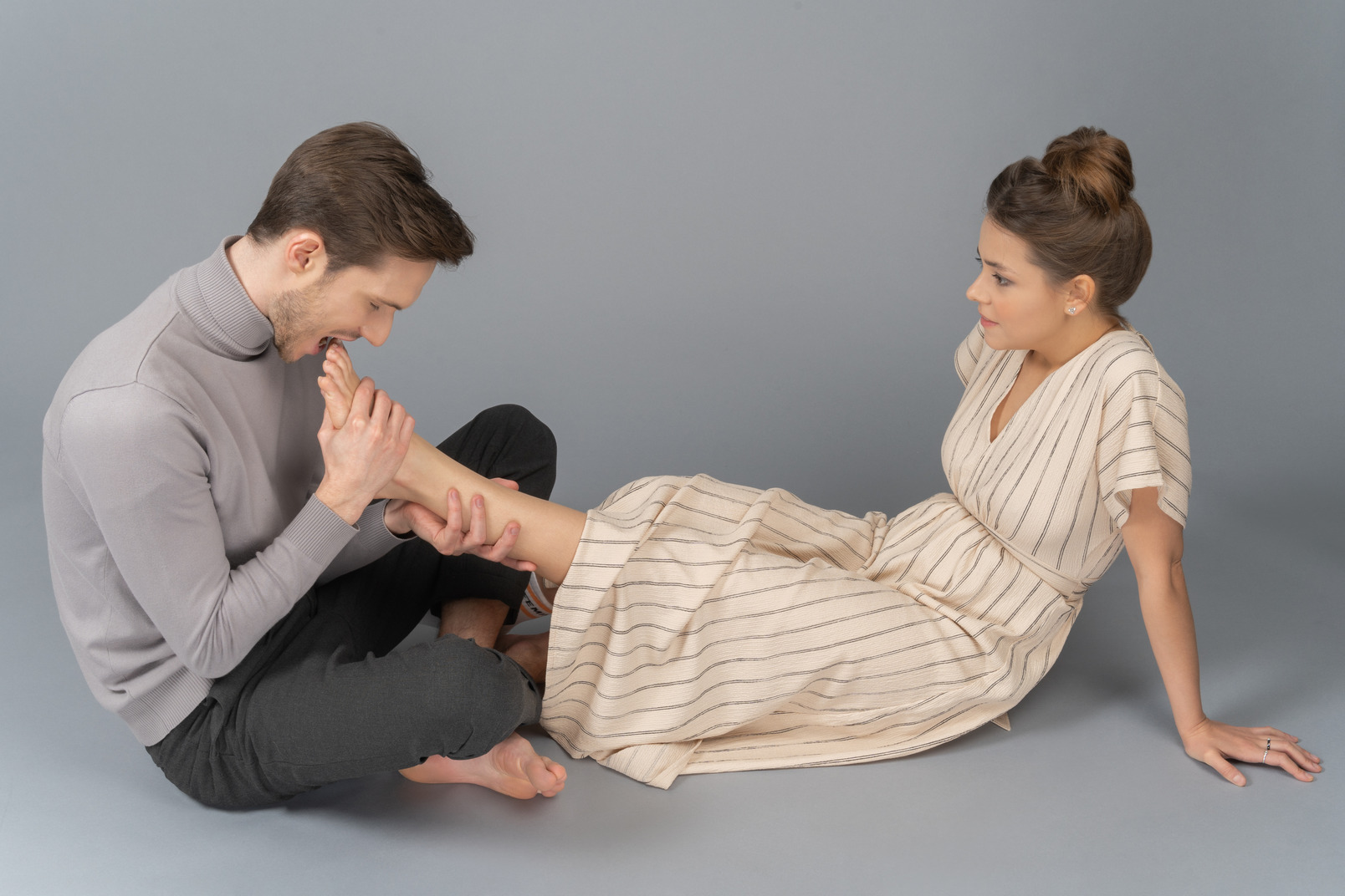 A young man is about to bite woman`s toenails