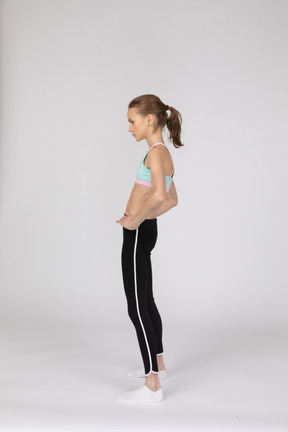 Vue latérale d'une adolescente en tenue de sport mettant les mains sur les hanches