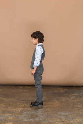 プロファイルに立っている灰色のスーツの少年