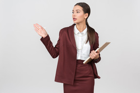 Atraente mulher formalmente vestida com uma prancheta apontando para algo