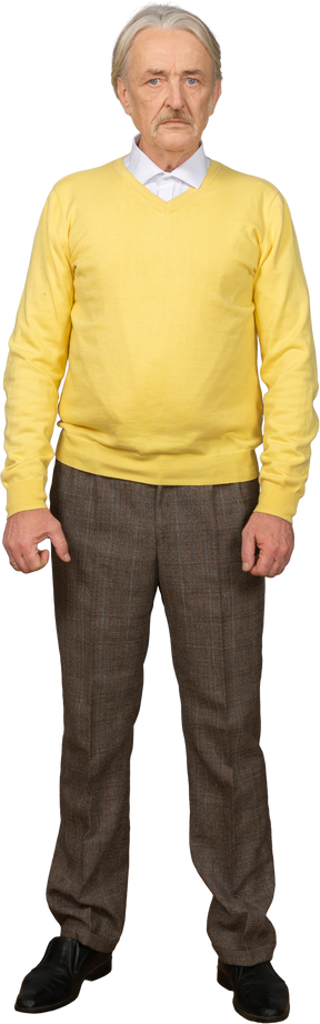 一个沮丧的老人，穿着一件黄色的套衫，看着相机的前视图