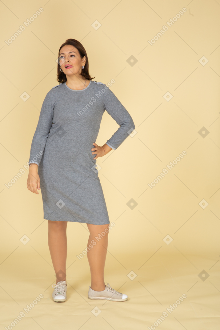 Front view of a woman in grey dress posing with hand on hip