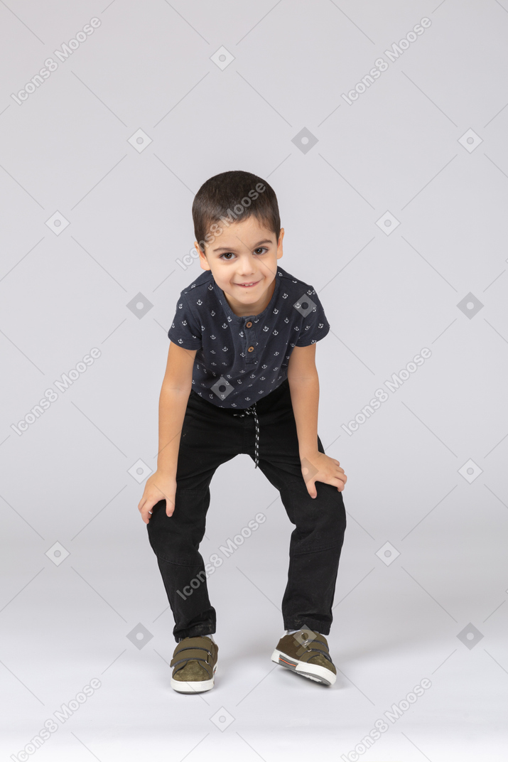 Front view of a cute boy squatting and looking at camera