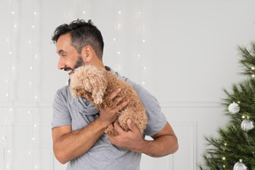 A man holding a dog in front of a christmas tree