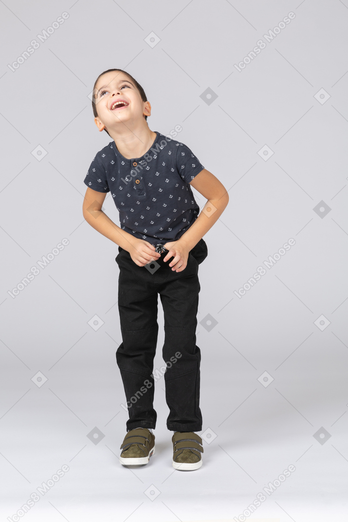 Vista frontal de un niño feliz en ropa casual mirando hacia arriba