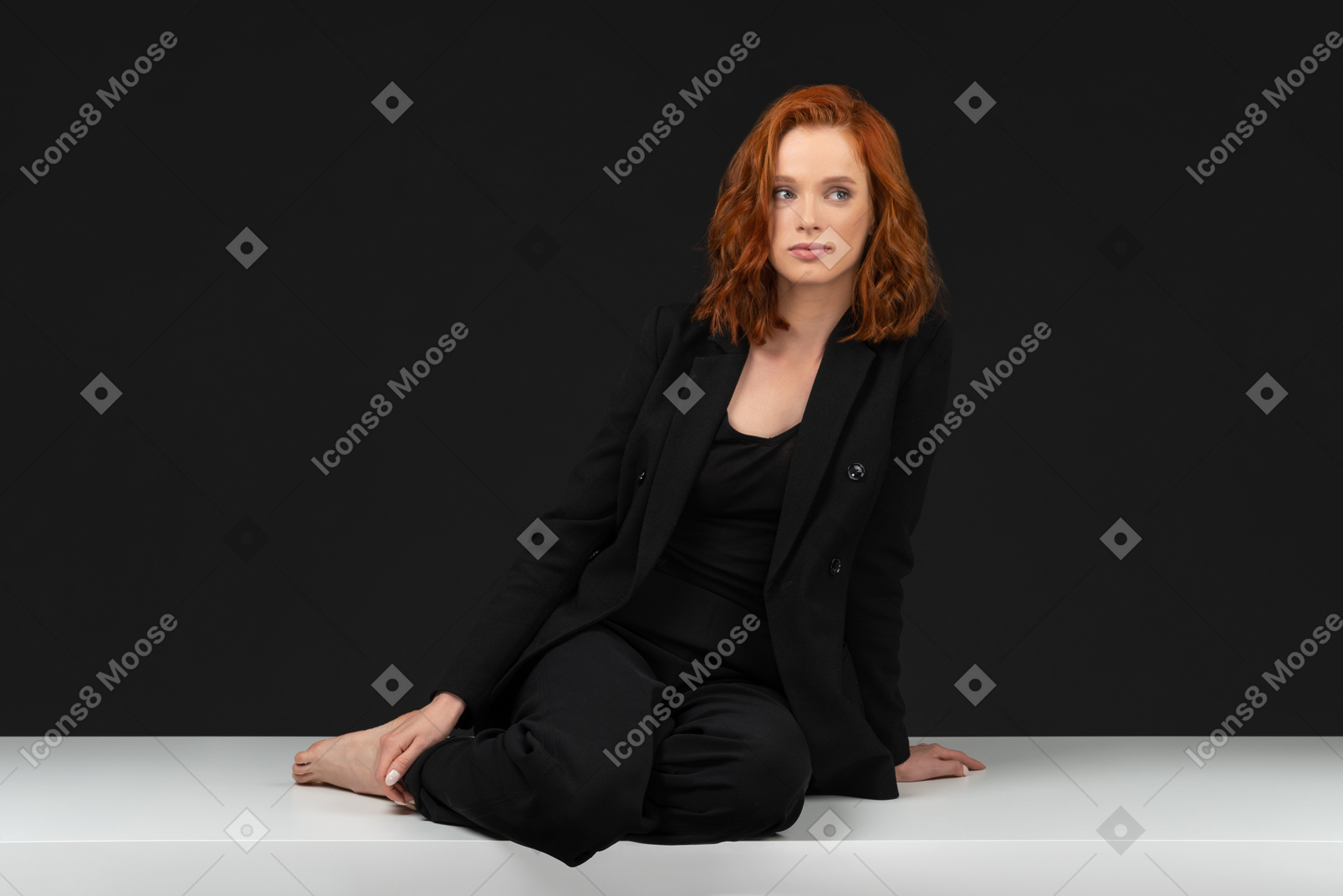 A frontal view of the cute young girl dressed in black and sitting on the table