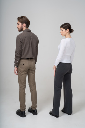 Three-quarter back view of a young couple in office clothing standing still