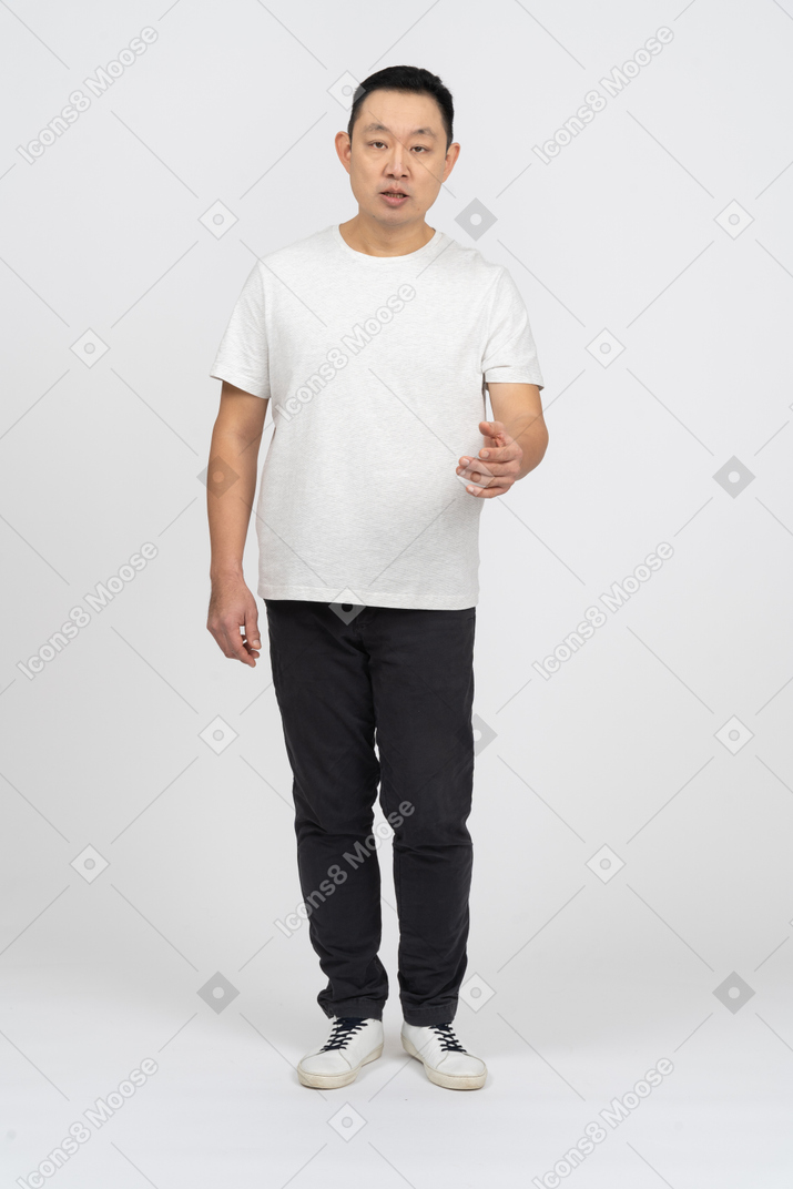 Vista frontale di un uomo in abiti casual in piedi con il braccio esteso e guardando la fotocamera