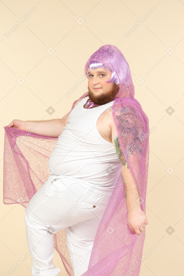 Young overweight man in violet fairy cape standing in violet fairy cape