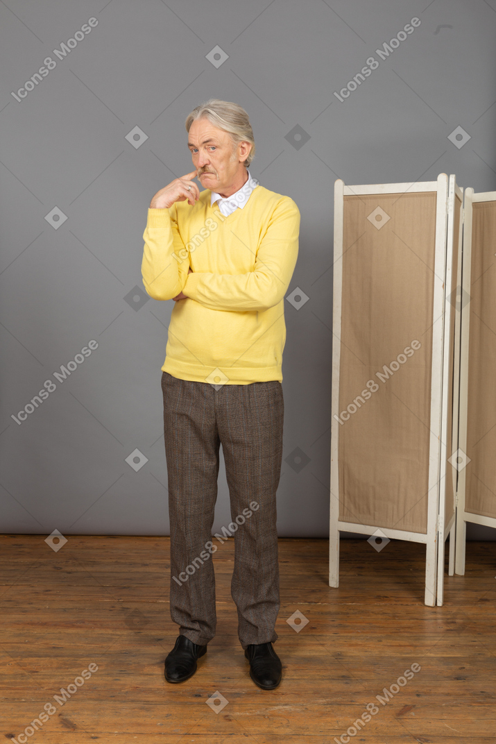 Vista frontal de um homem idoso pensativo apontando para a bochecha