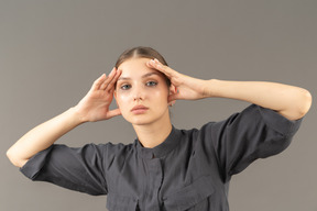 Vue de face d'une jeune femme en combinaison avec une peau propre touchant le visage