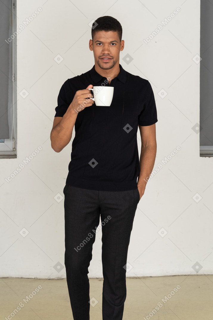 검은 바지와 티셔츠 들고 컵에 젊은 남자