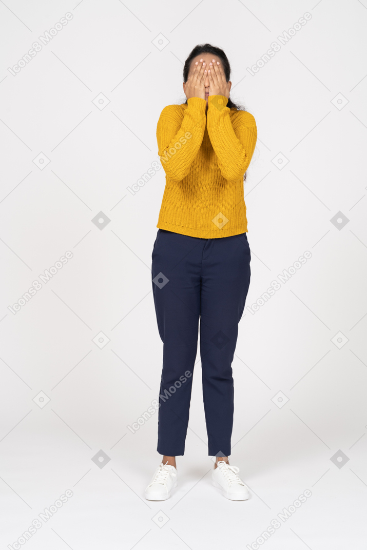 Front view of a girl in casual clothes covering face with hands