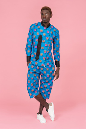 Black man in blue pajamas standing on the pink background