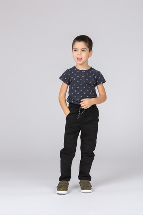 Vue de face d'un garçon mignon dans des vêtements décontractés posant avec la main dans la poche