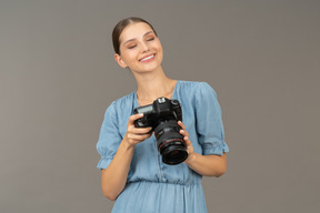 Front view of a smiling young woman in blue checking pictures