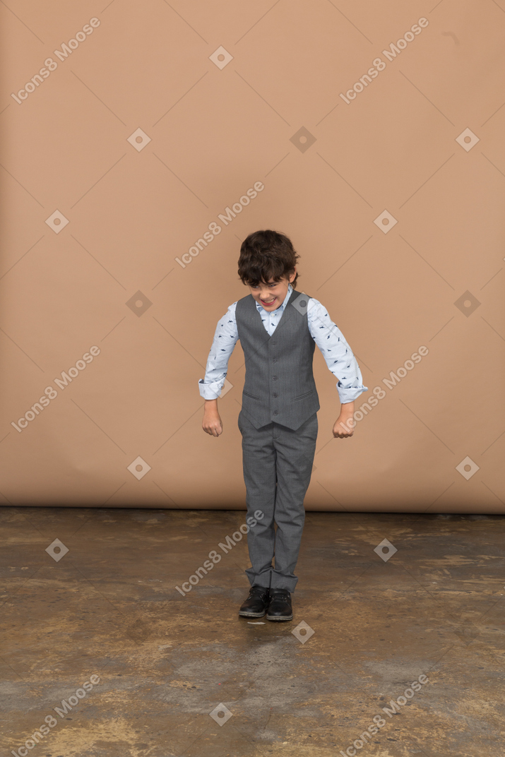 Front view of a boy in suit looking down and outstretching arms