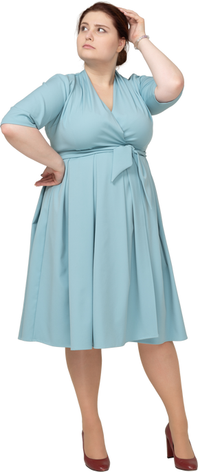 Vue de face d'une femme en robe bleue posant avec la main sur la hanche