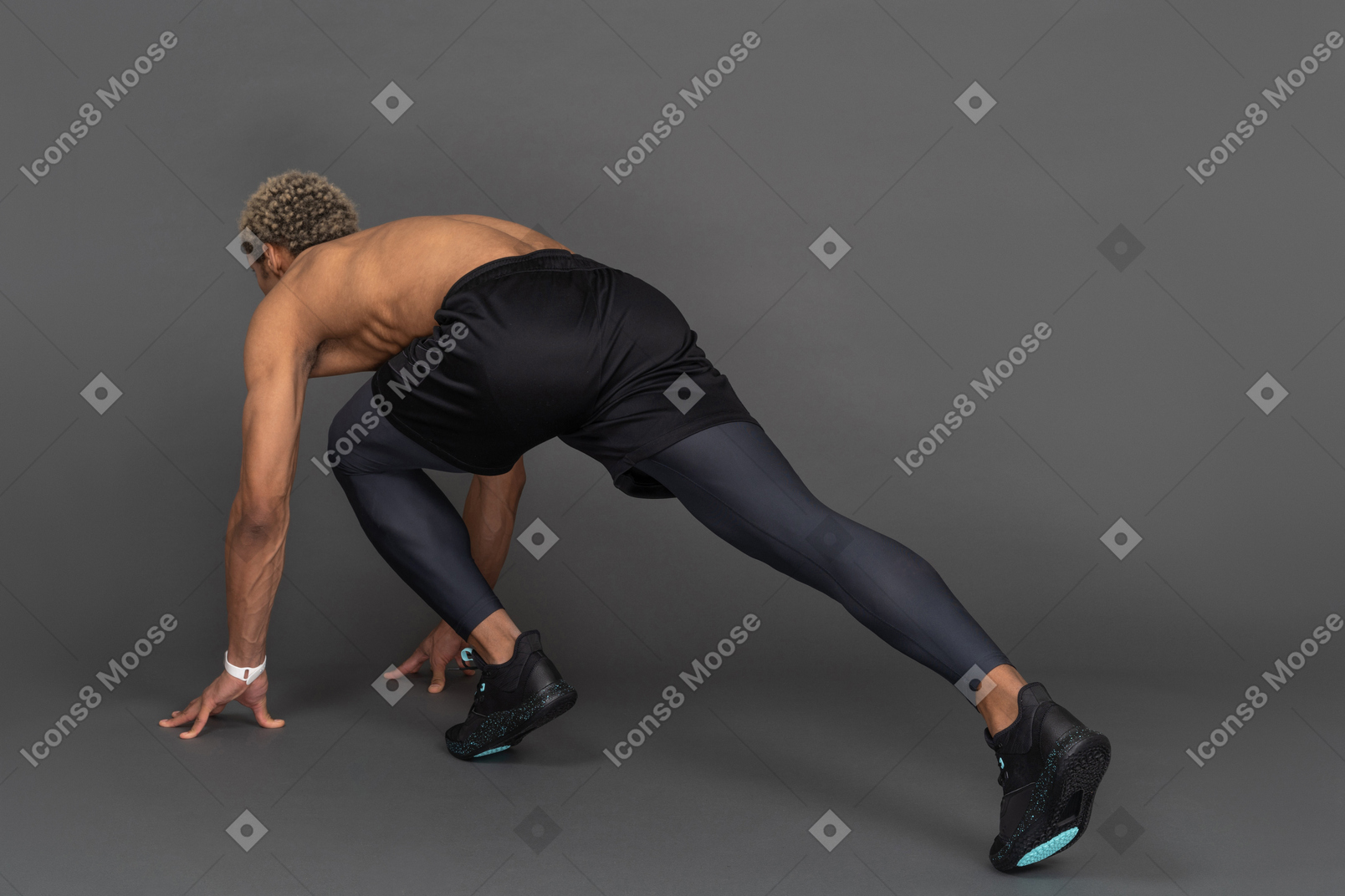 Three-quarter back view of a shirtless dark-skinned sprinter ready to run