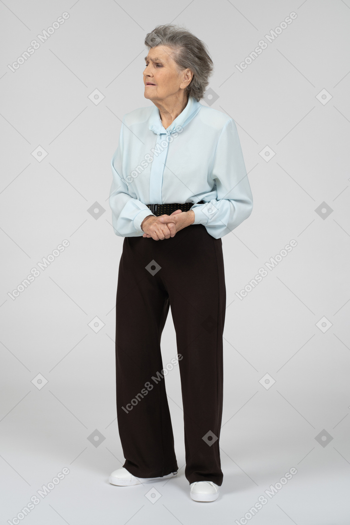 Front view of an old woman looking sad with clasped hands