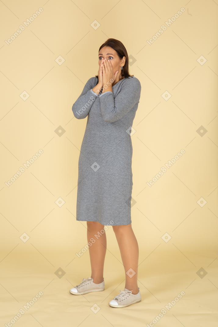 Mulher impressionada em um vestido cinza em pé de perfil