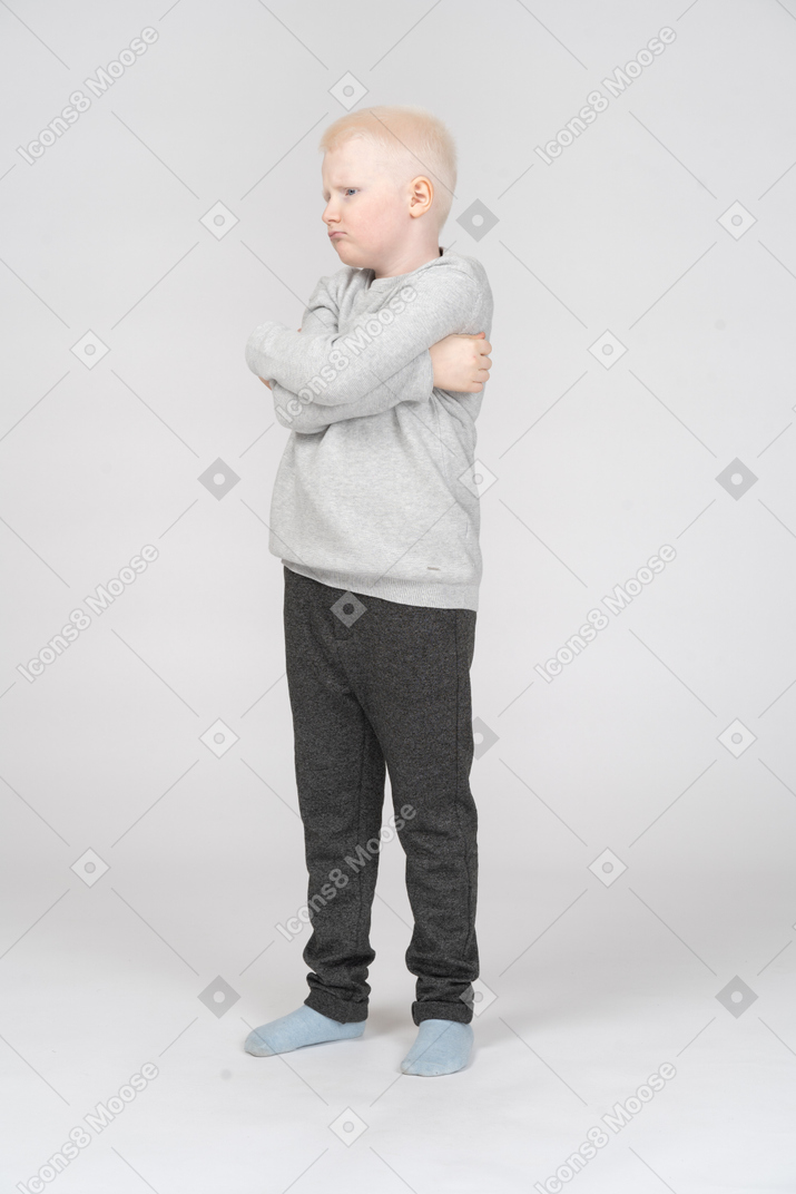 Vista de tres cuartos de un niño pequeño con las manos cruzadas