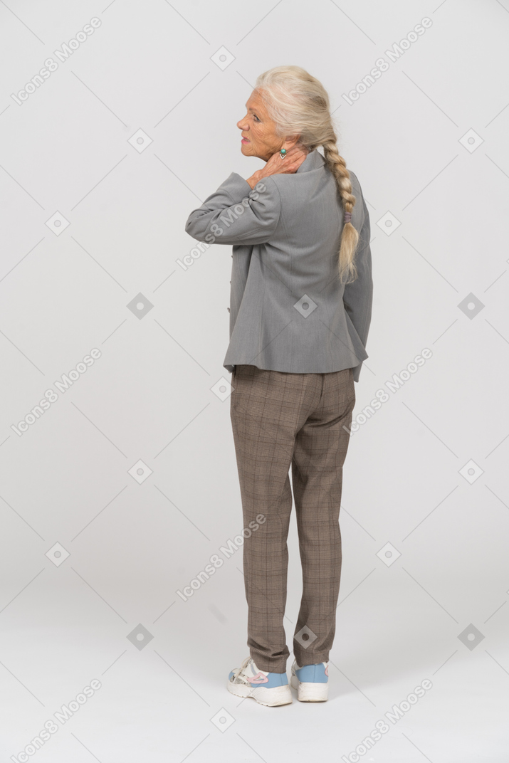 Rear view of an old lady in suit toching her neck