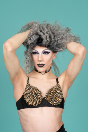 Drag queen con reggiseno borchiato che si tira su i capelli