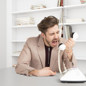 Man yelling into a rotary phone