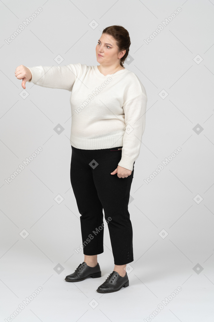 Triste mujer de talla grande mostrando el pulgar hacia abajo