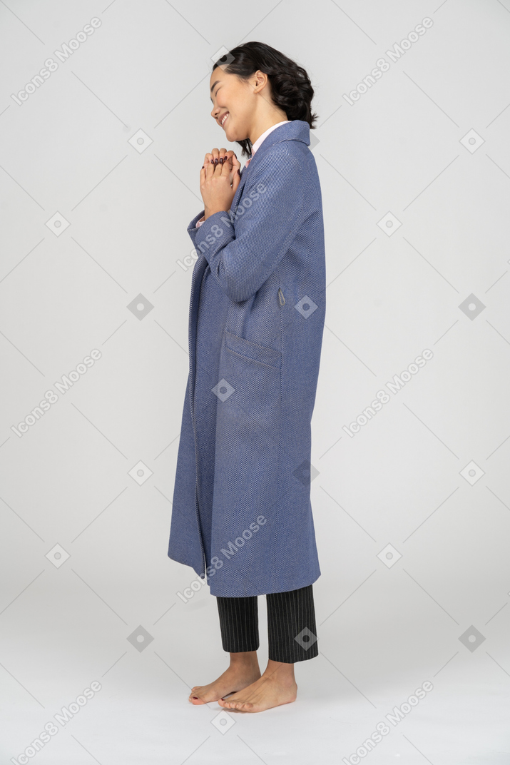 Cheerful woman in blue coat with folded hands