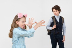 Petite fille faisant des grimaces et un écolier se moquant d'elle