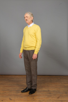 Three-quarter view of a sad old man in a yellow pullover looking at camera