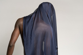 Back view of a young afro man covered with a dark blue shawl looking down