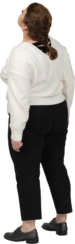 Rear view of a plump woman in casual clothes looking up